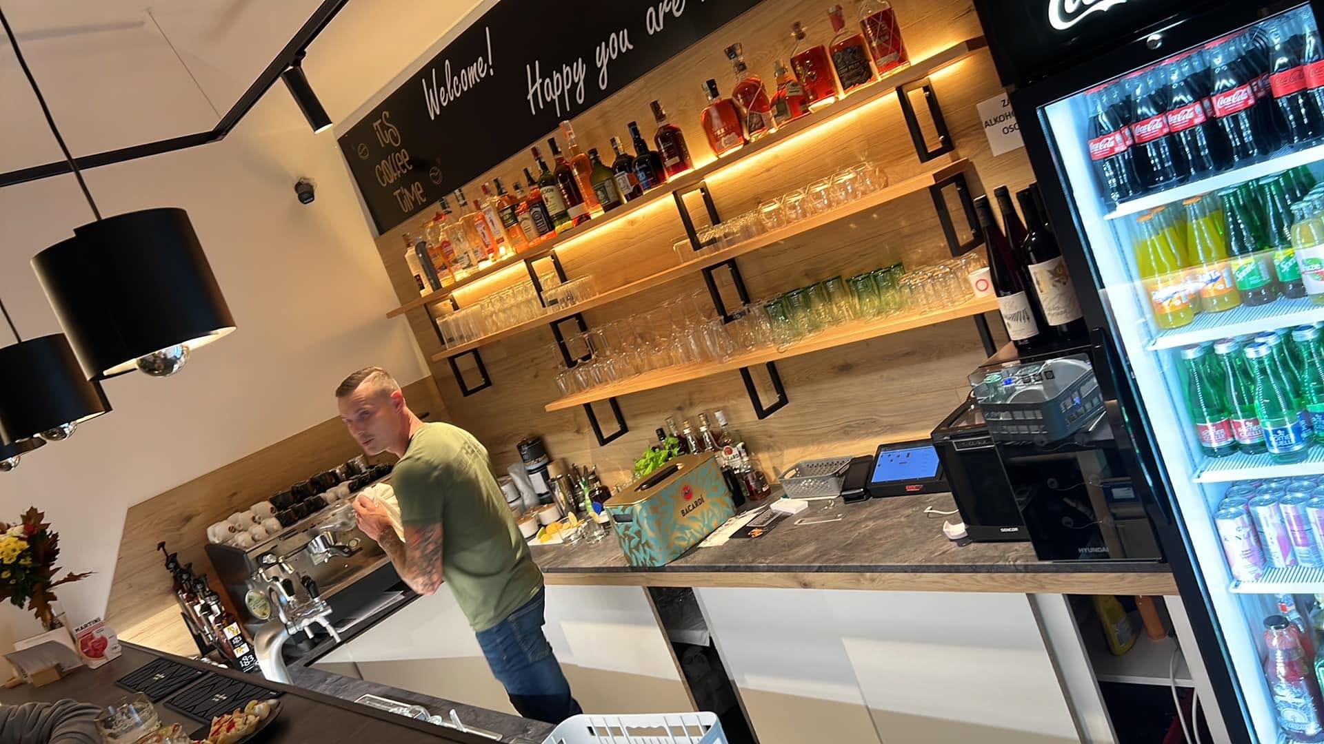 Bar v Kafe Klubu s policemi s nápoji a kávovarem
